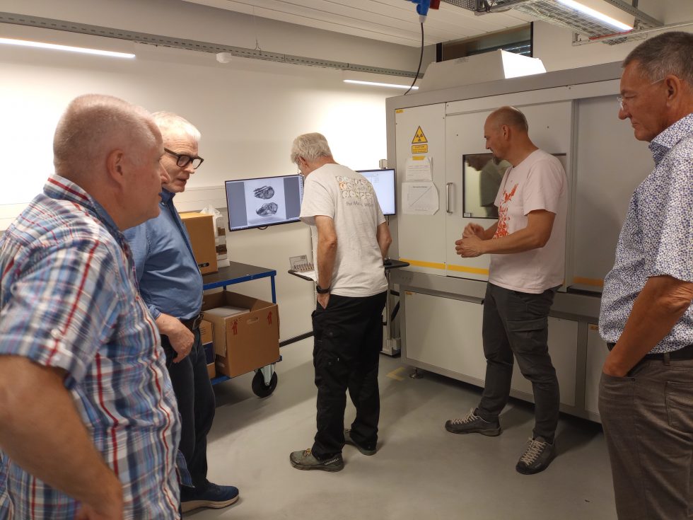 Five men standing around a digitising machine